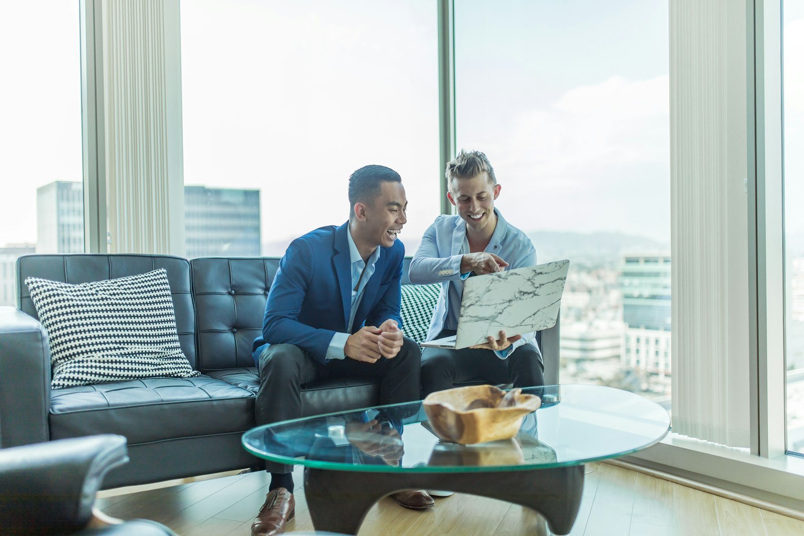 Two professionals in business suits seated together in a serious one-on-one consultation, discussing documents.
