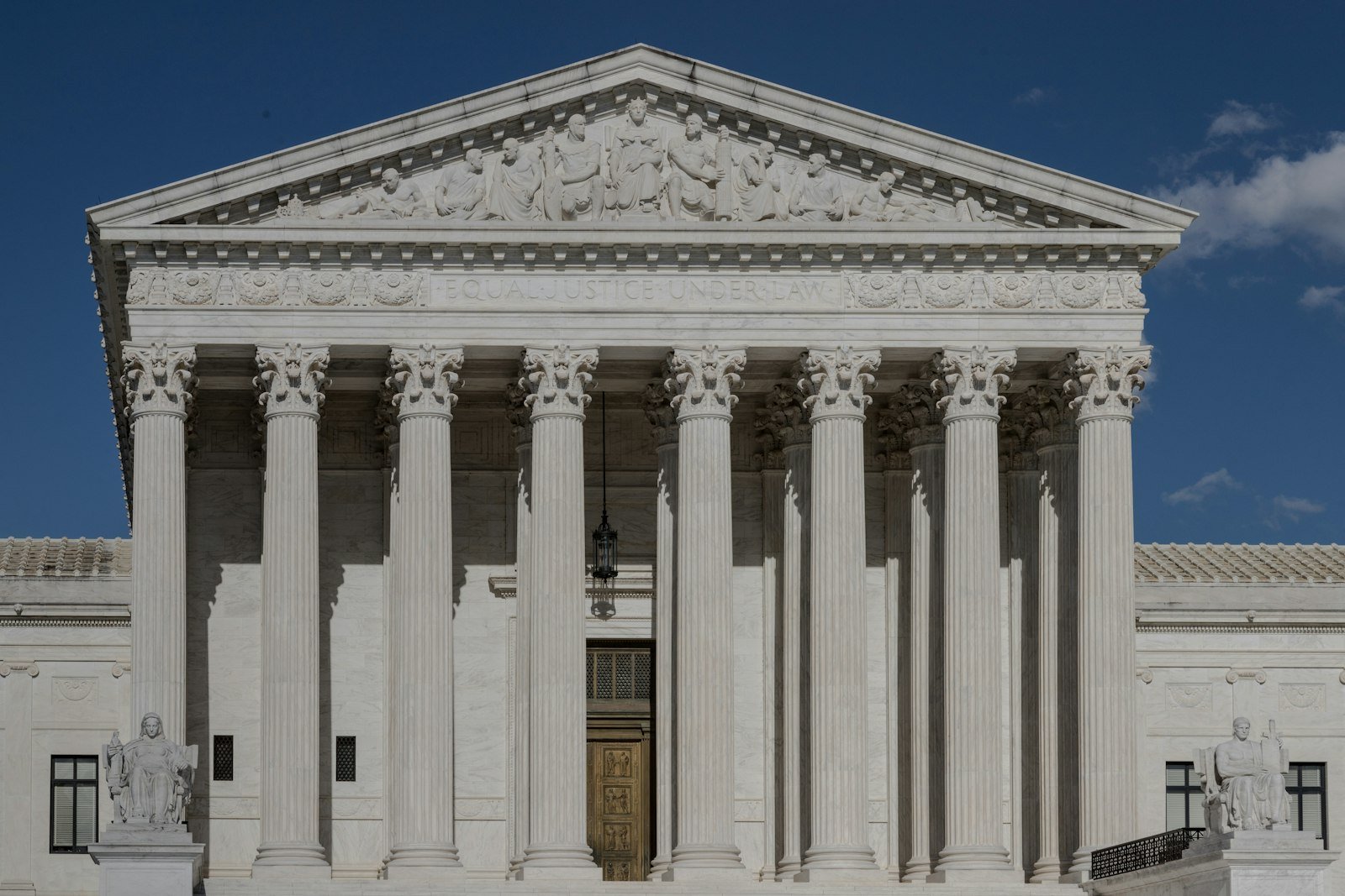 The United States Supreme Court building in Washington, D.C., with its imposing marble columns rising under a clear sky.